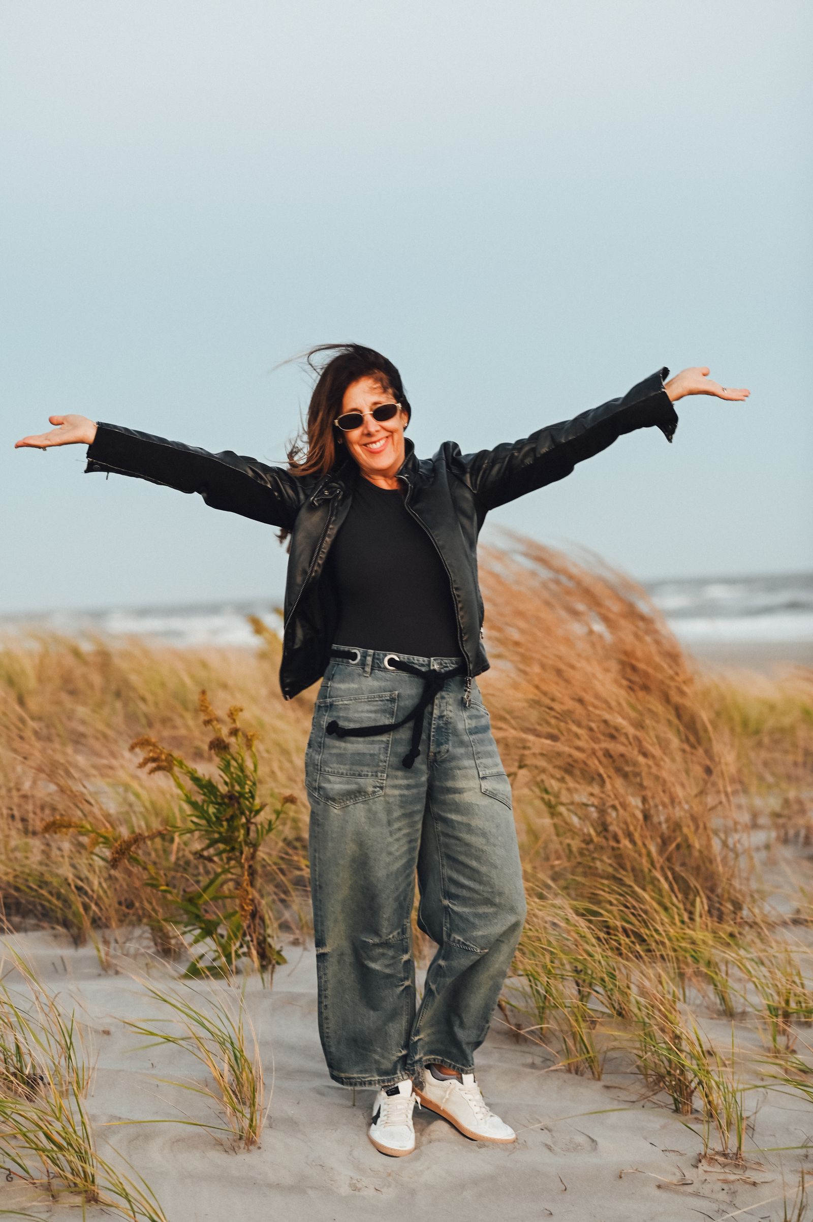 Helene on the beach with her arms spread wide