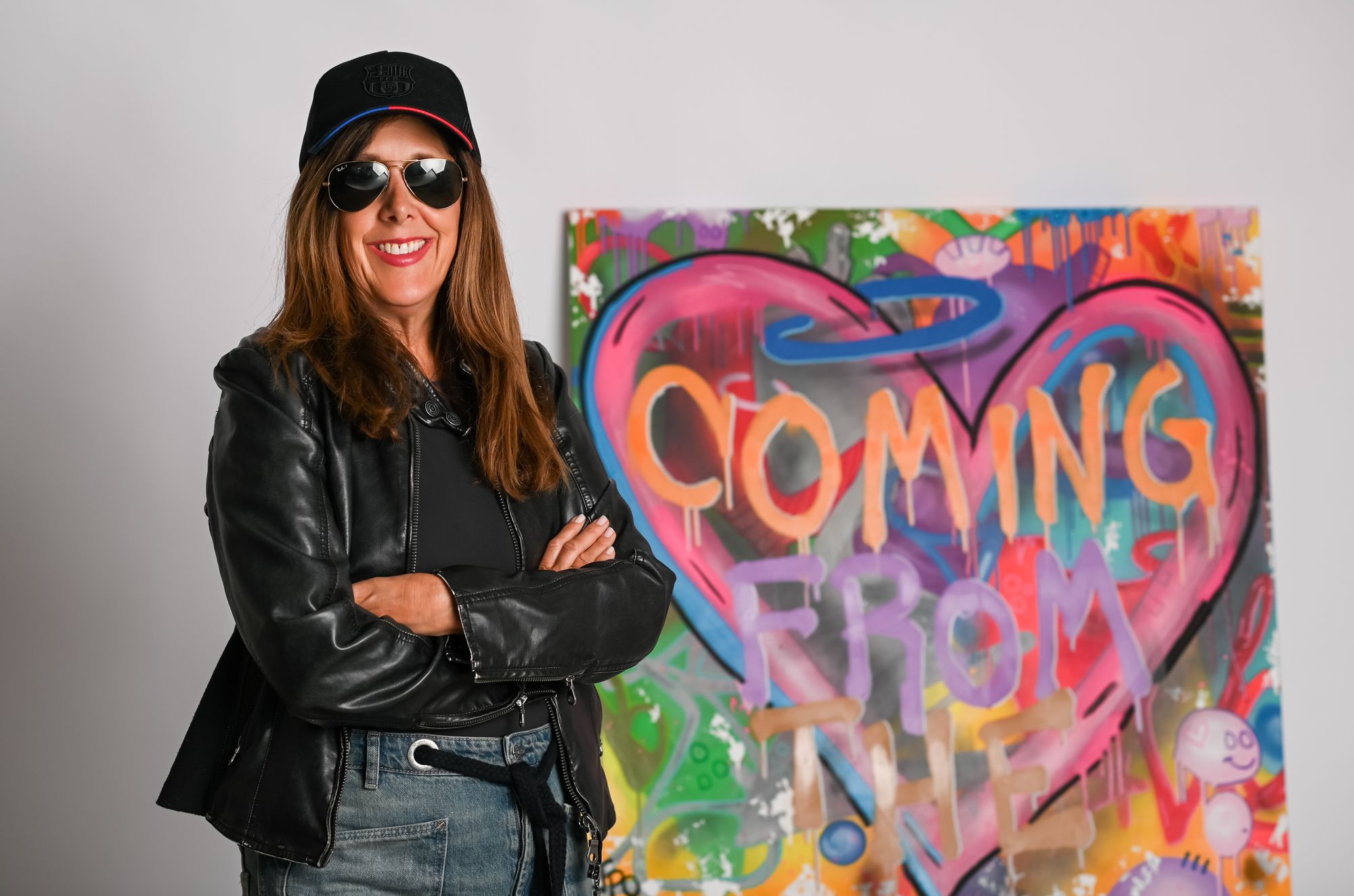 Helene beside a graffiti painting of a heart that reads Coming From The Heart
