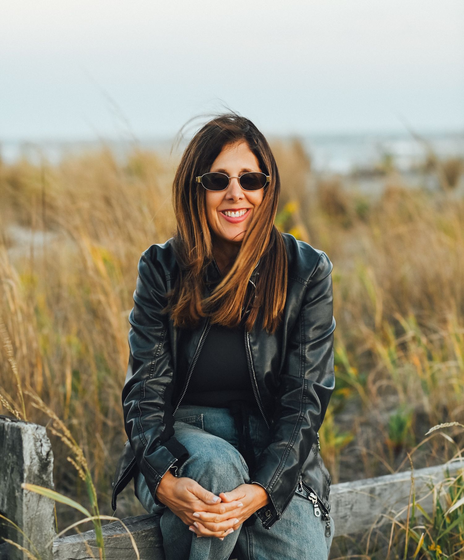 Helene sitting on a weathered fence in the dunes at the Jersey Shore